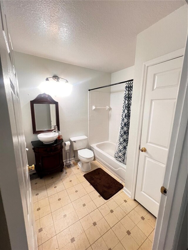 bathroom with toilet, shower / bath combo, vanity, and a textured ceiling