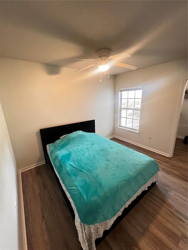 bedroom featuring ceiling fan, baseboards, and wood finished floors