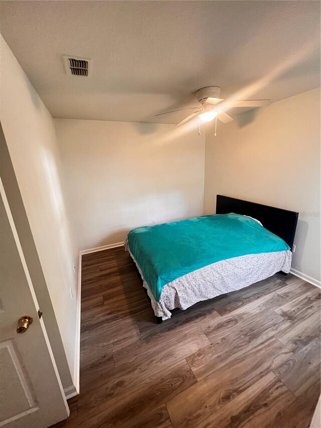 bedroom with visible vents, baseboards, a ceiling fan, and wood finished floors