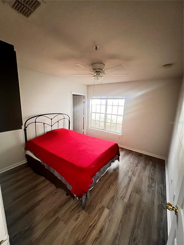 bedroom featuring visible vents, a ceiling fan, baseboards, and wood finished floors