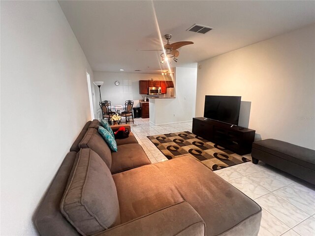 living area featuring a ceiling fan, visible vents, and baseboards