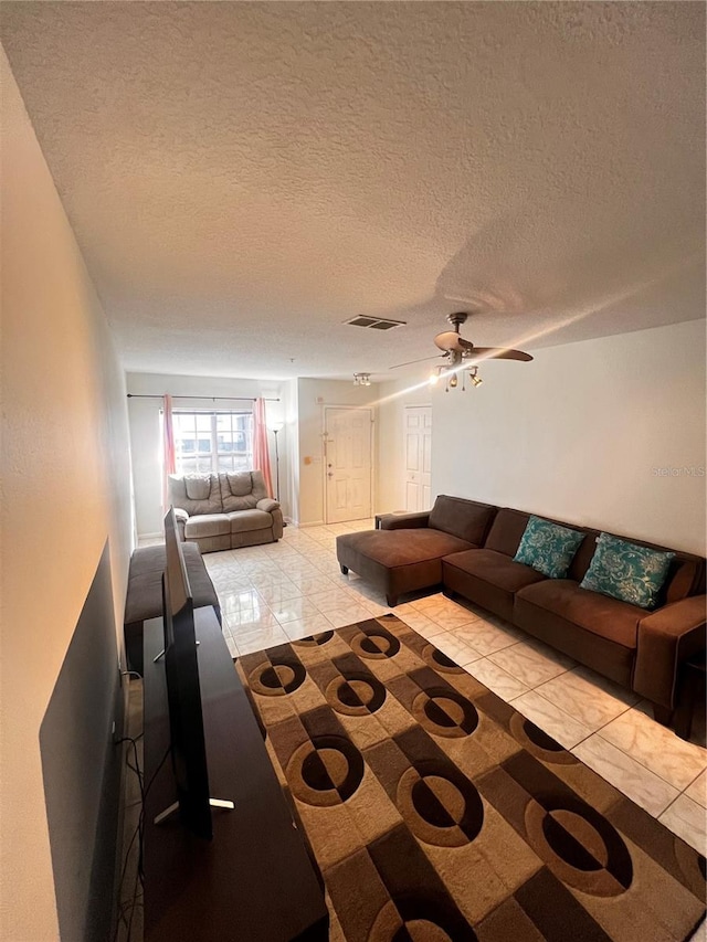 living room with a textured ceiling, visible vents, and ceiling fan