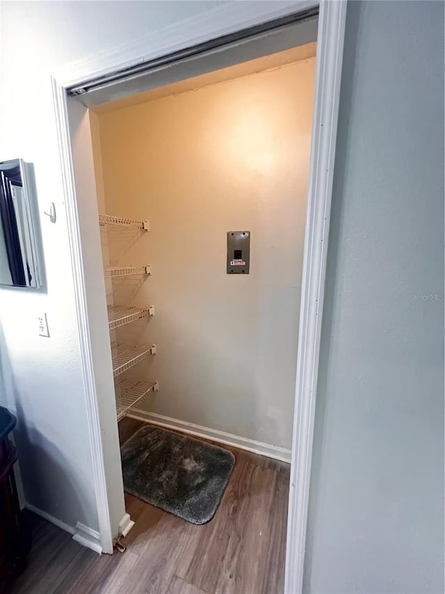 laundry area featuring baseboards, wood finished floors, and laundry area