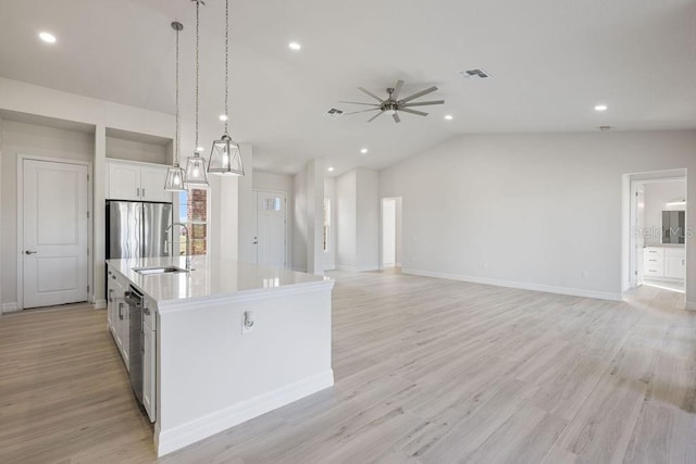 kitchen with sink, appliances with stainless steel finishes, an island with sink, white cabinets, and decorative light fixtures