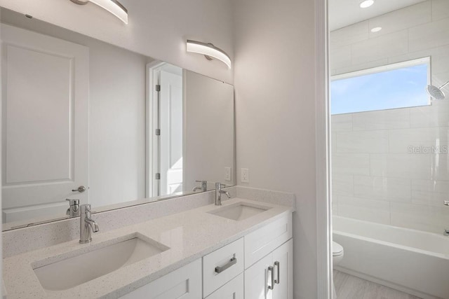 full bathroom featuring vanity, tiled shower / bath combo, and toilet