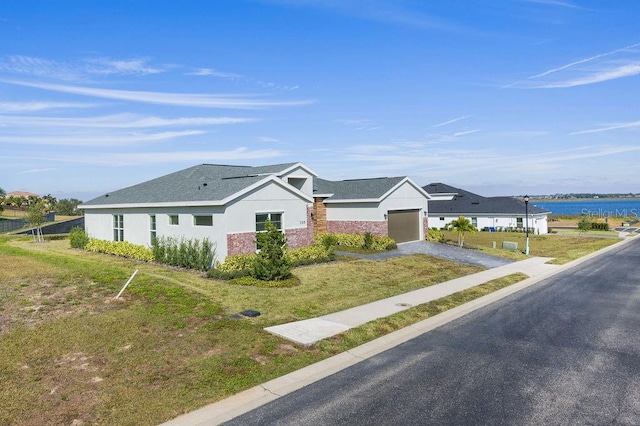 single story home featuring a garage, a water view, and a front lawn