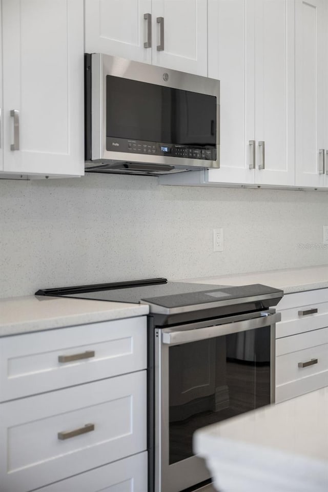 kitchen with white cabinetry, backsplash, and stainless steel appliances