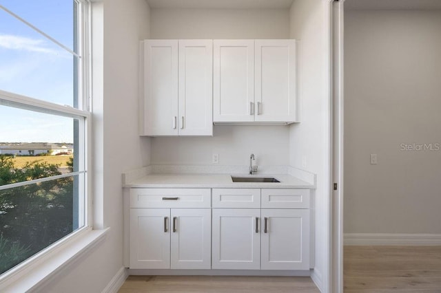 bar featuring sink, white cabinets, and light hardwood / wood-style flooring