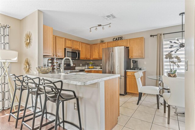 2881 Kokomo Loop, Haines City, FL 33844 - kitchen featuring a kitchen breakfast bar, light tile floors, appliances with stainless steel finishes, backsplash, and track lighting