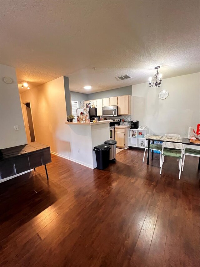 kitchen featuring a chandelier, stainless steel appliances, a textured ceiling, and dark wood-type flooring