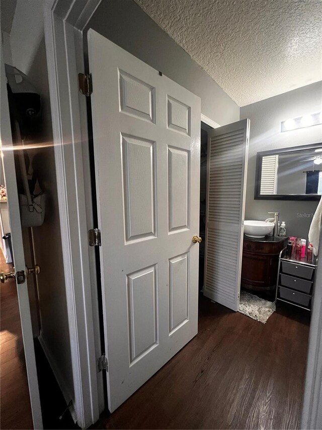 bathroom featuring a textured ceiling, vanity with extensive cabinet space, and hardwood / wood-style flooring