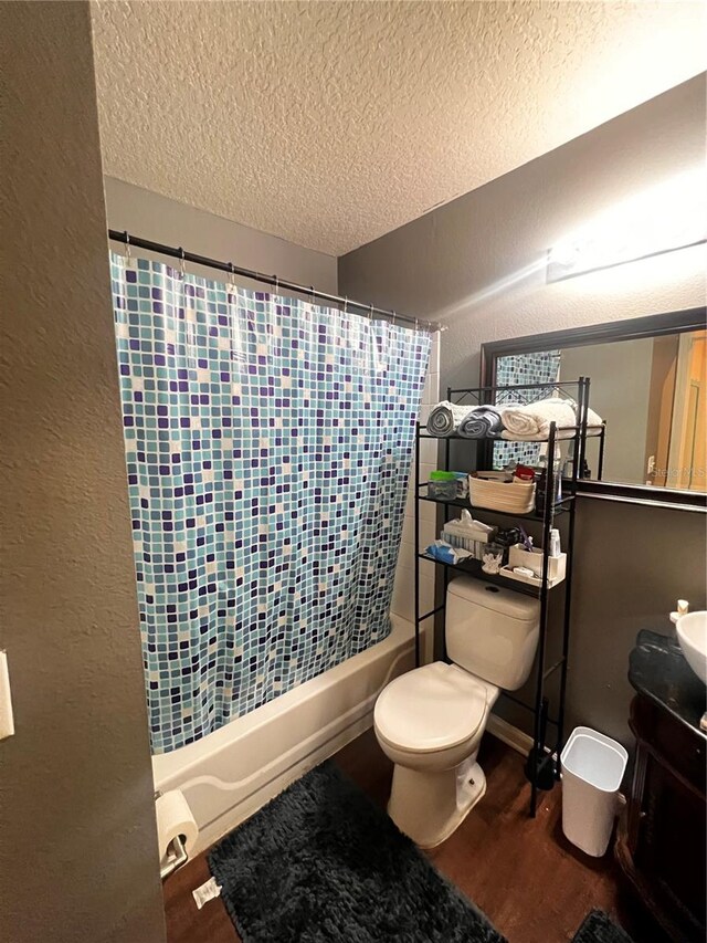 full bathroom featuring toilet, hardwood / wood-style floors, a textured ceiling, vanity, and shower / bathtub combination with curtain