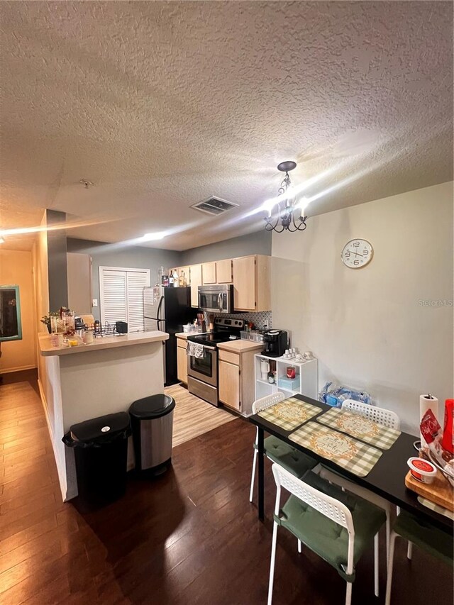 kitchen with light brown cabinets, stainless steel appliances, a textured ceiling, dark hardwood / wood-style floors, and an inviting chandelier