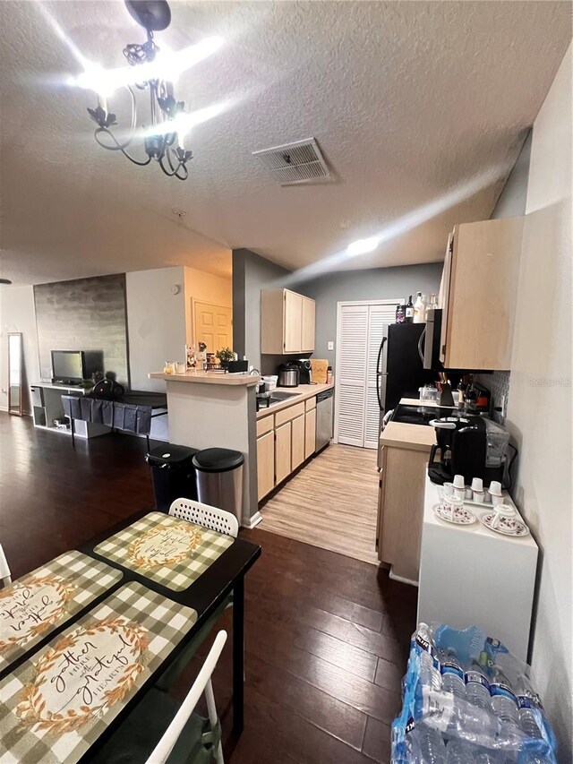 kitchen with light brown cabinetry, sink, a chandelier, wood-type flooring, and a textured ceiling