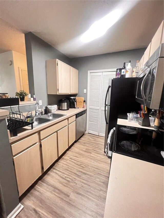 kitchen with light brown cabinetry, light hardwood / wood-style flooring, appliances with stainless steel finishes, and sink