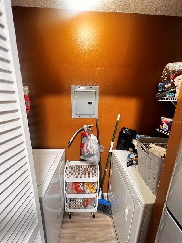 clothes washing area featuring washer and clothes dryer and light wood-type flooring