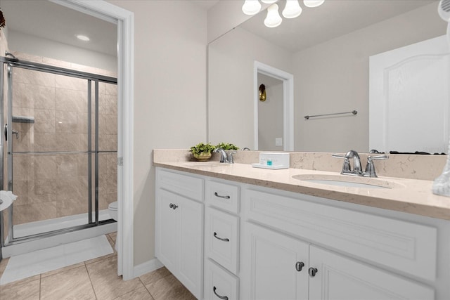 bathroom featuring double vanity, tile flooring, a shower with shower door, and toilet