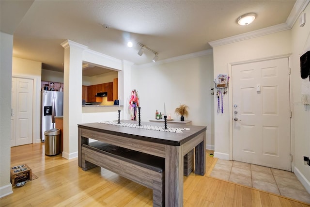 interior space with stainless steel fridge, light tile floors, rail lighting, and crown molding