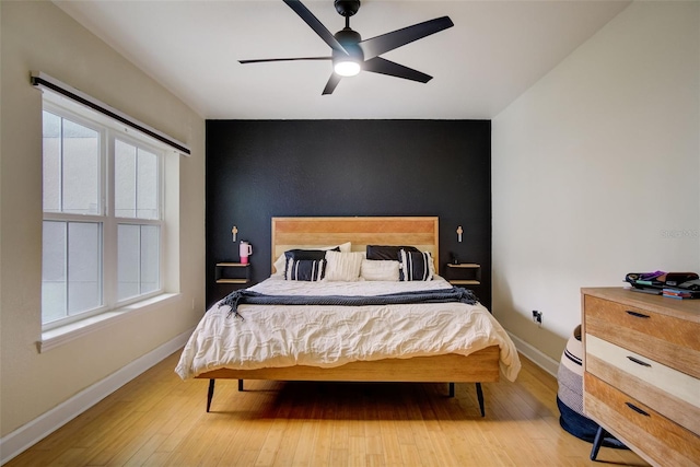 bedroom featuring light hardwood / wood-style floors, ceiling fan, and multiple windows