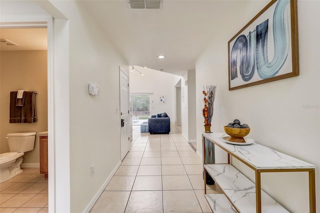 hall with light tile flooring and lofted ceiling