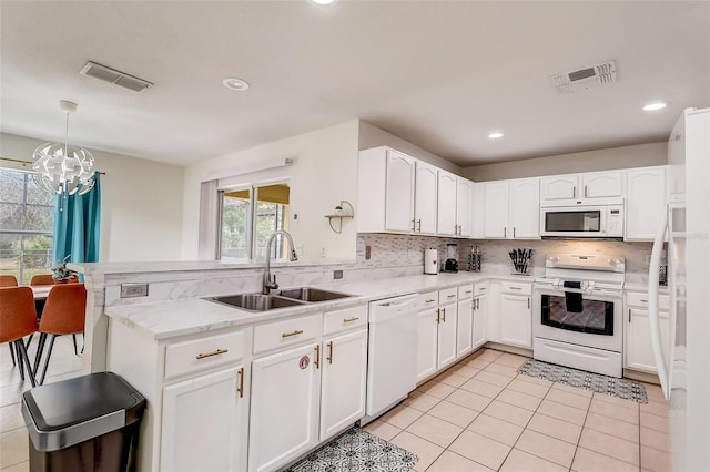 kitchen featuring white appliances, a notable chandelier, white cabinets, and sink