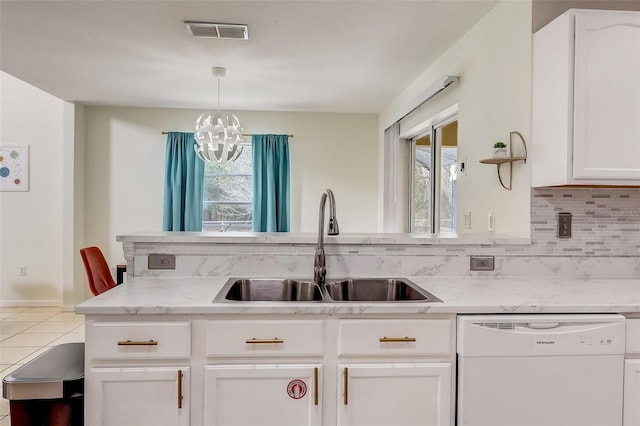 kitchen featuring backsplash, white dishwasher, a wealth of natural light, and an inviting chandelier