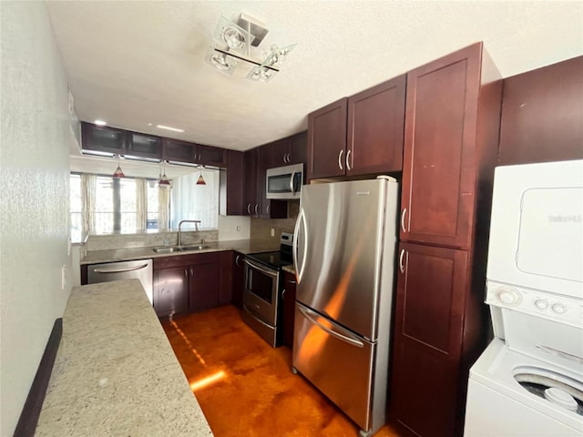 kitchen featuring stainless steel appliances, a textured ceiling, sink, and stacked washer and dryer