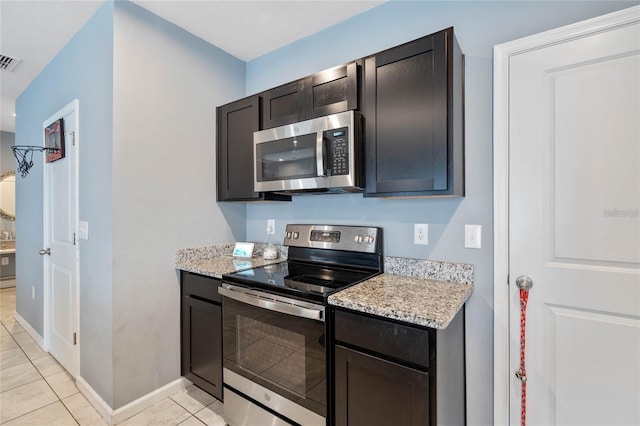 kitchen featuring light stone counters, light tile patterned floors, stainless steel appliances, and dark brown cabinetry