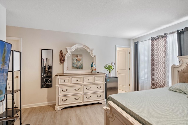 bedroom with a textured ceiling and light hardwood / wood-style floors