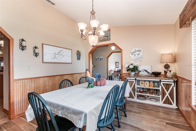 dining room with vaulted ceiling, hardwood / wood-style floors, and an inviting chandelier