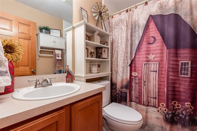 bathroom with a textured ceiling, oversized vanity, and toilet