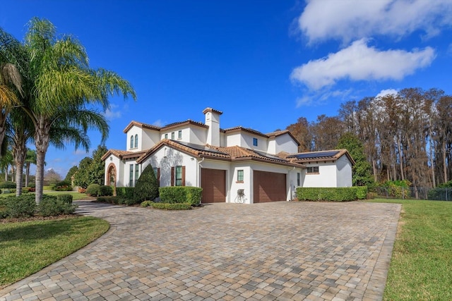 mediterranean / spanish-style house featuring a front yard and a garage