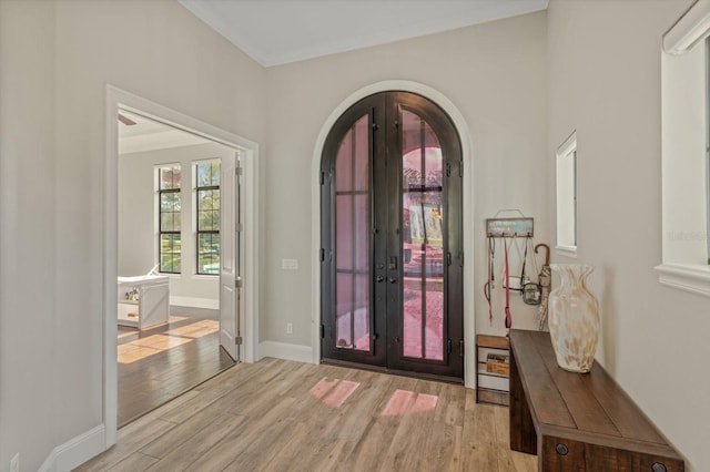 entryway with crown molding, light hardwood / wood-style floors, and french doors