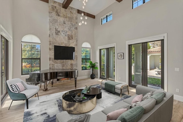 living room with plenty of natural light, beamed ceiling, a fireplace, and light wood-type flooring