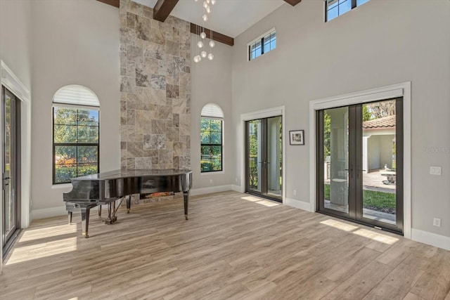 interior space with a high ceiling, french doors, beam ceiling, and light hardwood / wood-style flooring