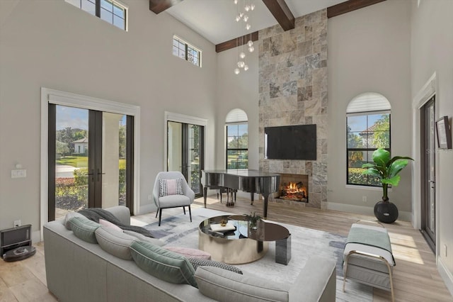 living room featuring beam ceiling, light hardwood / wood-style floors, plenty of natural light, and a tile fireplace