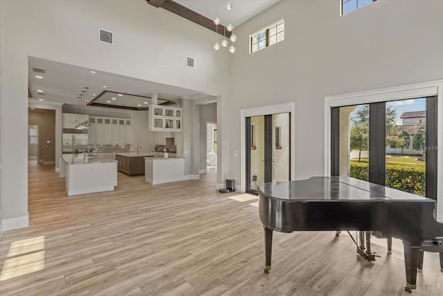 misc room with a high ceiling, french doors, a healthy amount of sunlight, and light wood-type flooring