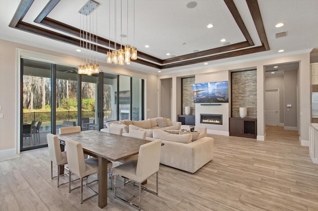 interior space featuring crown molding, a tray ceiling, light wood-type flooring, and an inviting chandelier