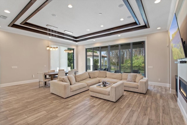 living room with crown molding, light hardwood / wood-style floors, and a raised ceiling