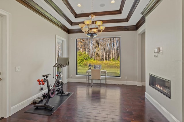 workout room featuring a chandelier, a tray ceiling, dark hardwood / wood-style flooring, and ornamental molding