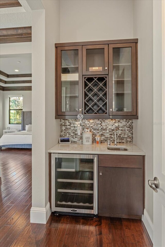 bar featuring sink, crown molding, dark hardwood / wood-style flooring, backsplash, and beverage cooler