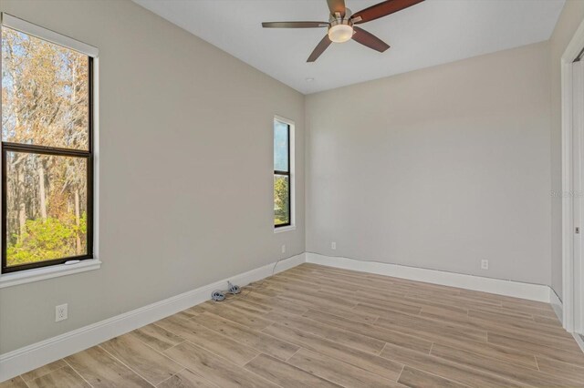 empty room with ceiling fan and light hardwood / wood-style flooring