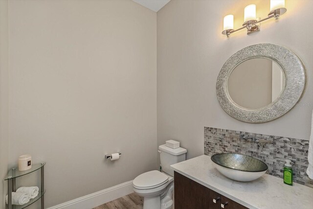 bathroom featuring hardwood / wood-style flooring, vanity, backsplash, and toilet