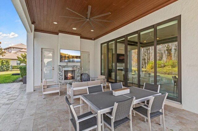 view of patio with an outdoor living space with a fireplace and ceiling fan