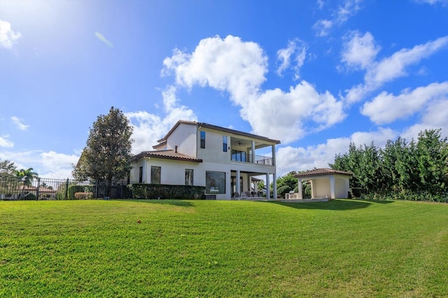 back of house featuring a lawn and a balcony