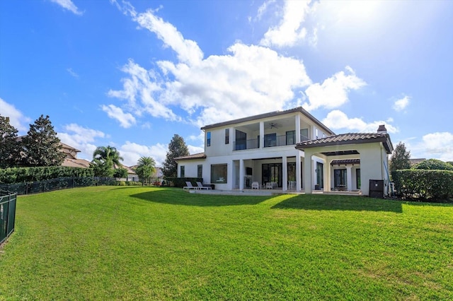 rear view of property featuring a lawn, a balcony, and a patio