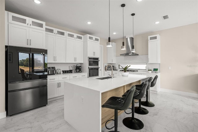 kitchen featuring an island with sink, sink, a kitchen breakfast bar, hanging light fixtures, and extractor fan