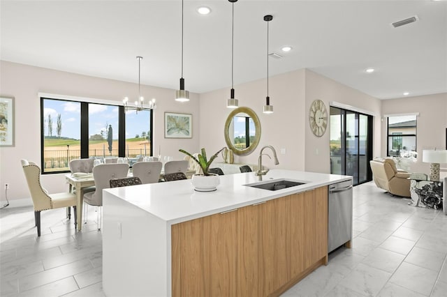 kitchen with an island with sink, sink, hanging light fixtures, dishwasher, and an inviting chandelier