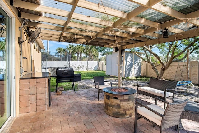 view of patio / terrace with a pergola, a shed, and an outdoor fire pit