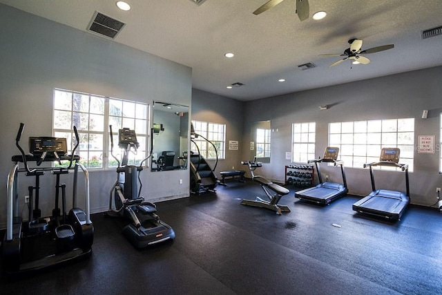 gym featuring ceiling fan, a textured ceiling, and a wealth of natural light